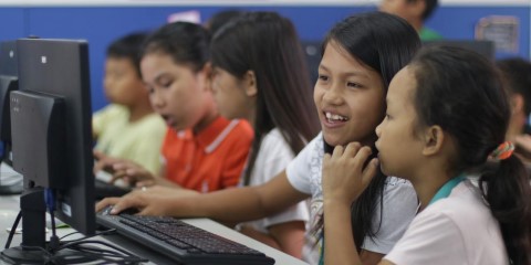 un grupo de niños sentados frente a una computadora