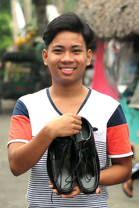 a young man holding a pair of black shoes