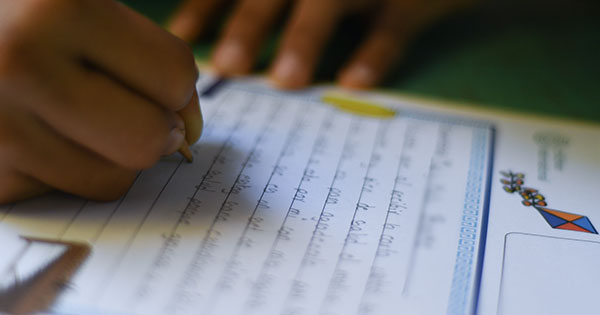 a person writing on a piece of paper with a pencil