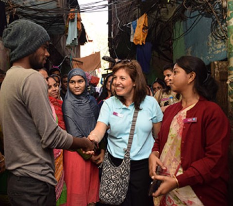 a group of people standing around a woman shaking hands