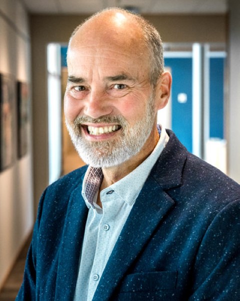 a man in a blue suit is smiling for the camera